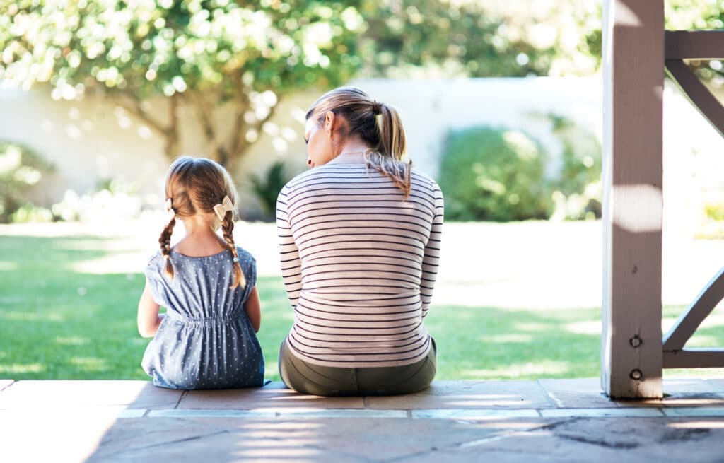 Mor og datter sitter sammen på en trapp utenfor huset. Brukt som illustrasjon i artikkel om advokat innen familierett
