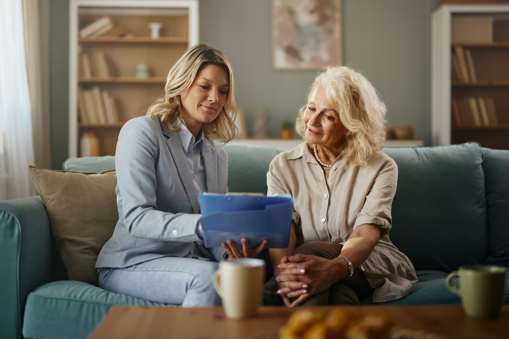 To kvinner går gjennom papirer om ektepakt og særkullsbarn i en varm og avslappet hjemmesetting med kaffekopper på bordet.